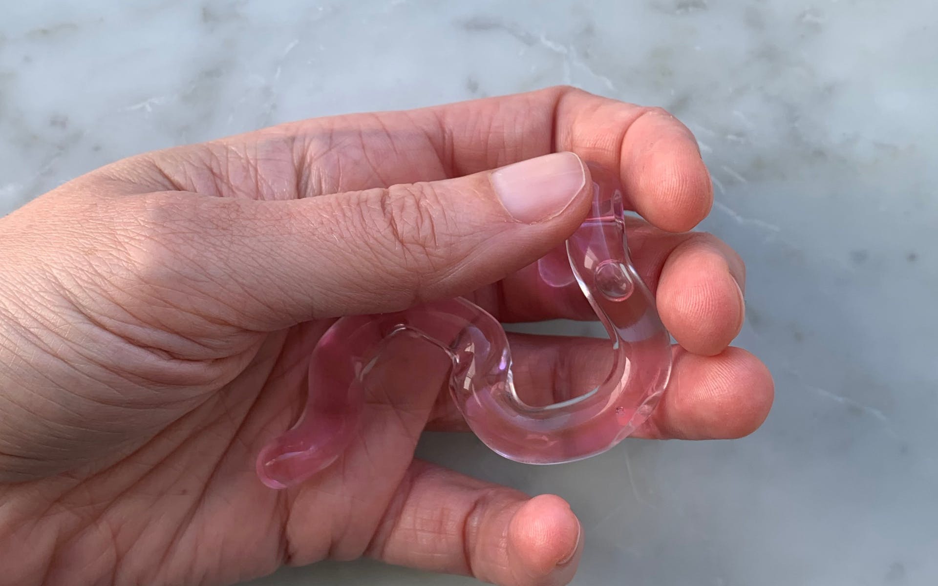 Hand holding pink glass tube-like object