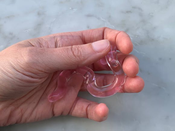 Hand holding pink glass tube-like object