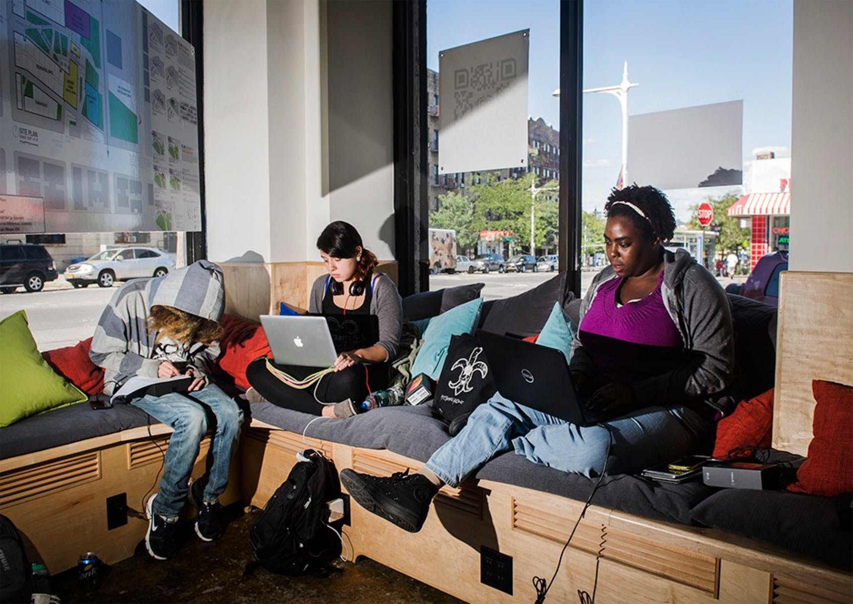 Students working on laptops in front of large windows