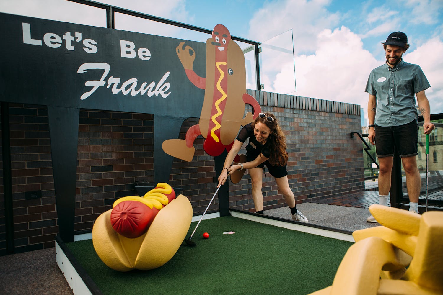 people playing mini golf course featuring giant hot dog