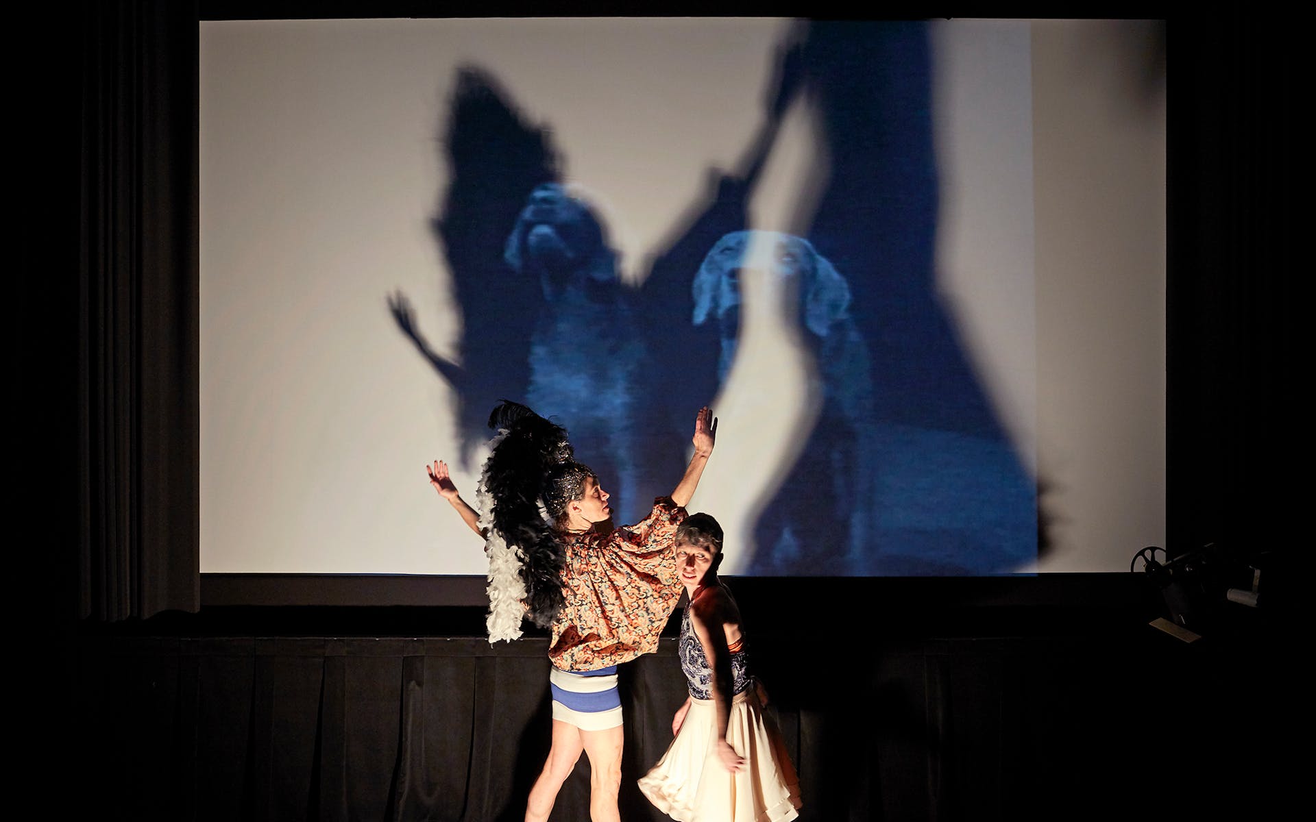 Two dancers in front of a screen.