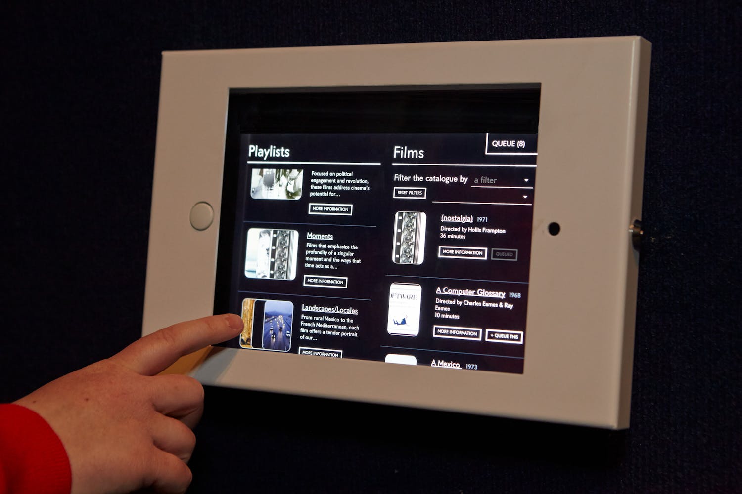 a child's hand reaches out to press a touch screen player.