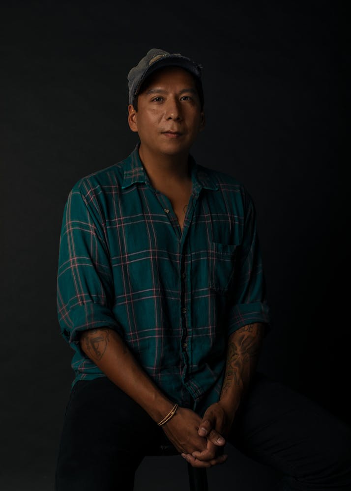 A seated man looks at the viewer.