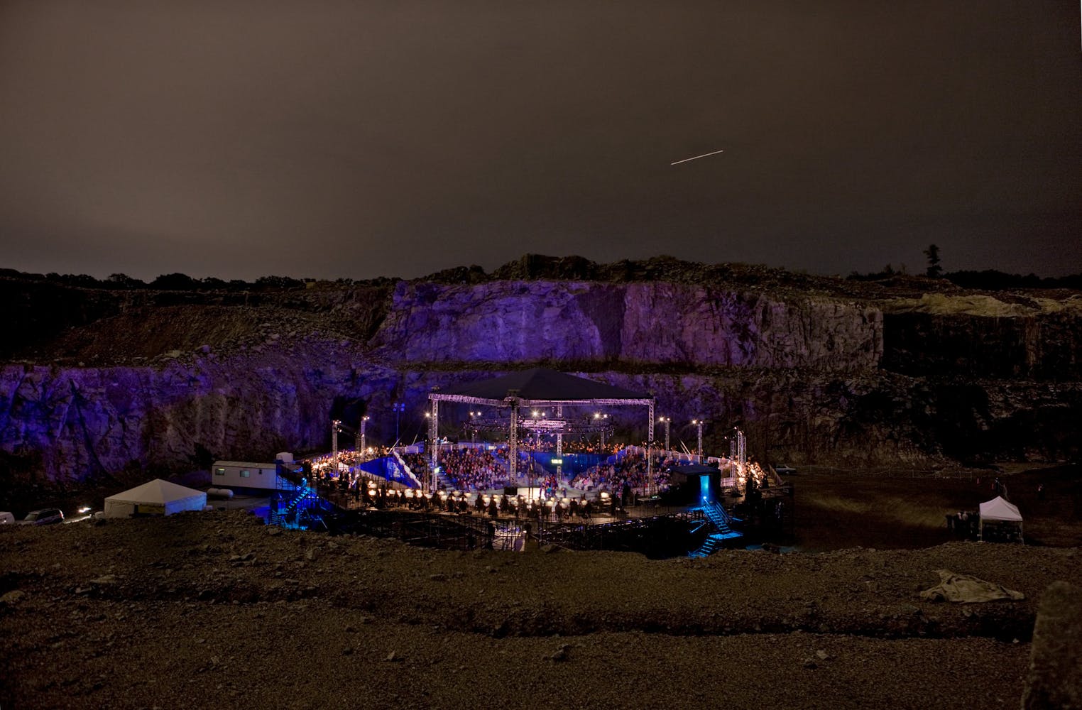 A large stage stands in a quarry at night.