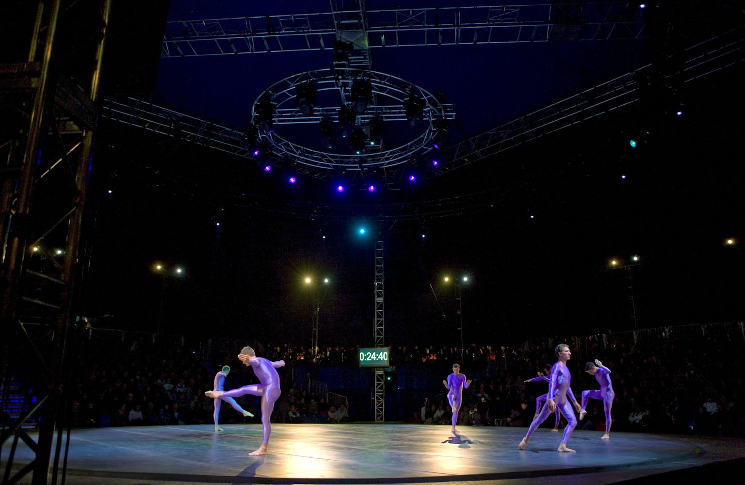 Dancers perform on a large stage in aquarry at night.