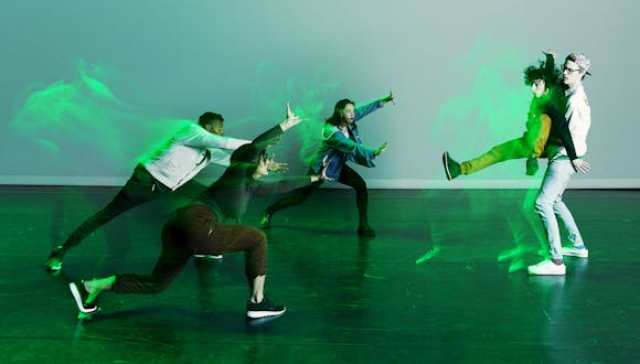 STRONGmovement dance group dancing illuminated by green lighting.