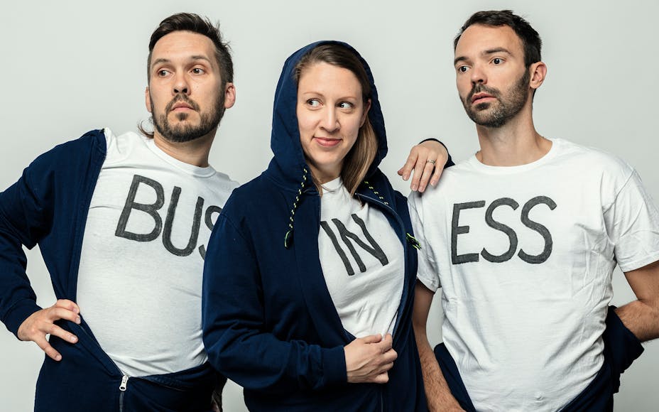 Members of Super Group wearing t-shirts that spell out: BUS IN ESS