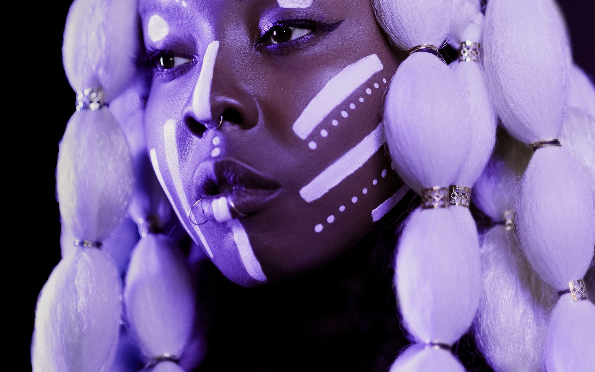 woman with facepaint and large beaded wig under purple light