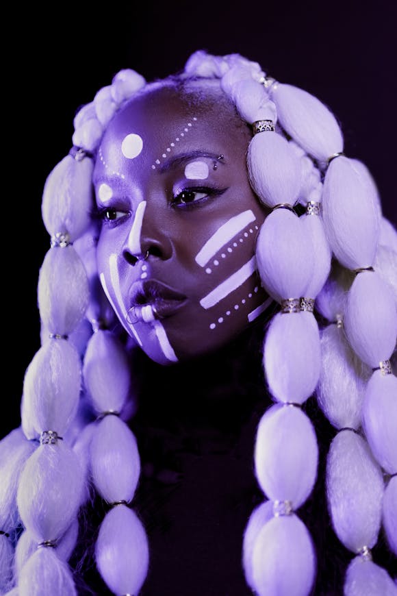 woman with facepaint and large beaded wig under purple light