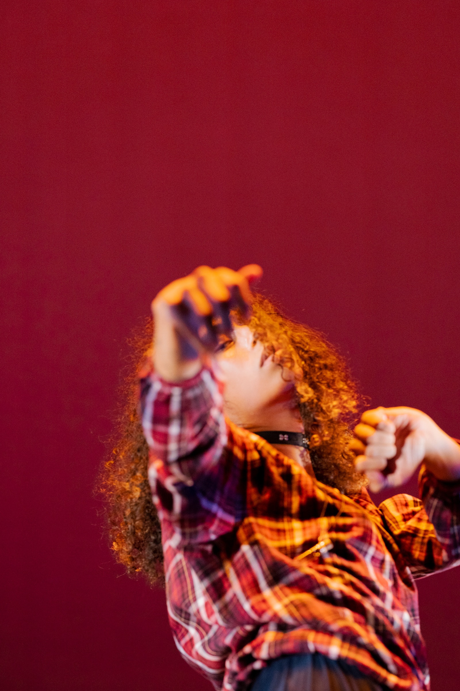 A dancer with light brown skin and curly, shoulder-length brown hair poses