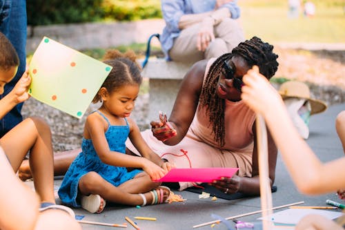 A mother sits with her daughter and does art making activities in the Minneapolis Sculpture Garden on a summer day.