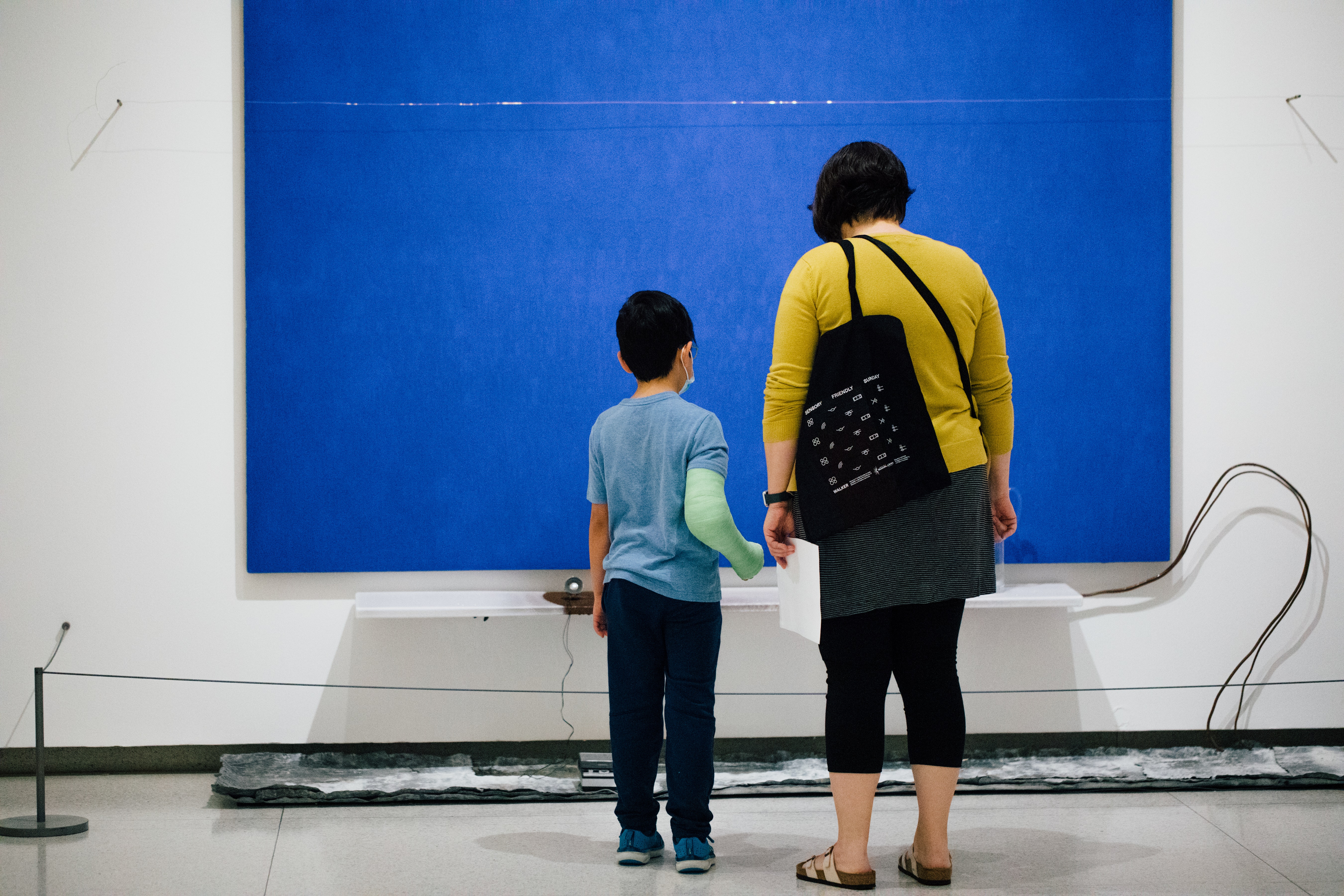 An adult and child looking at art, seen from behind