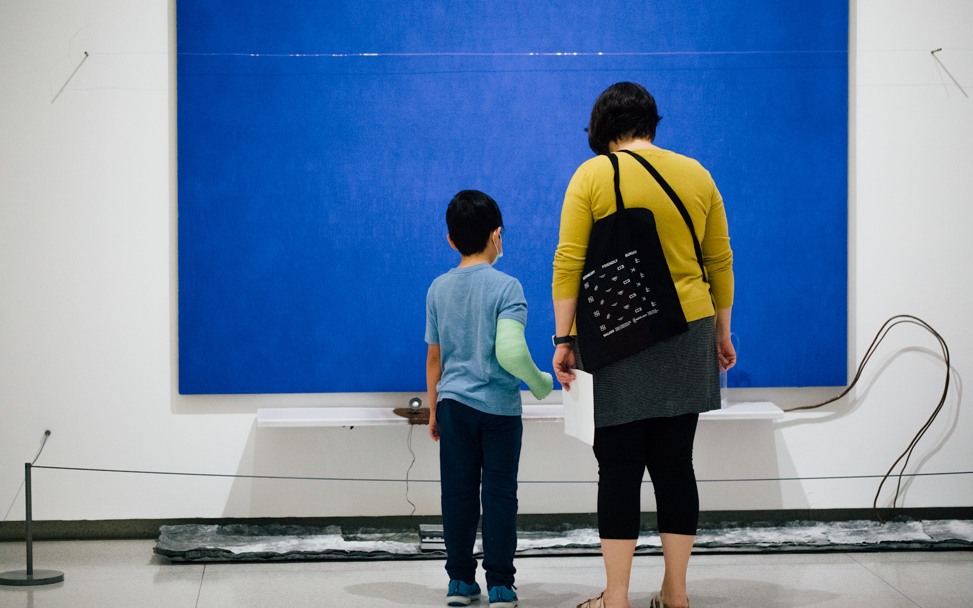 An adult and child looking at art, seen from behind