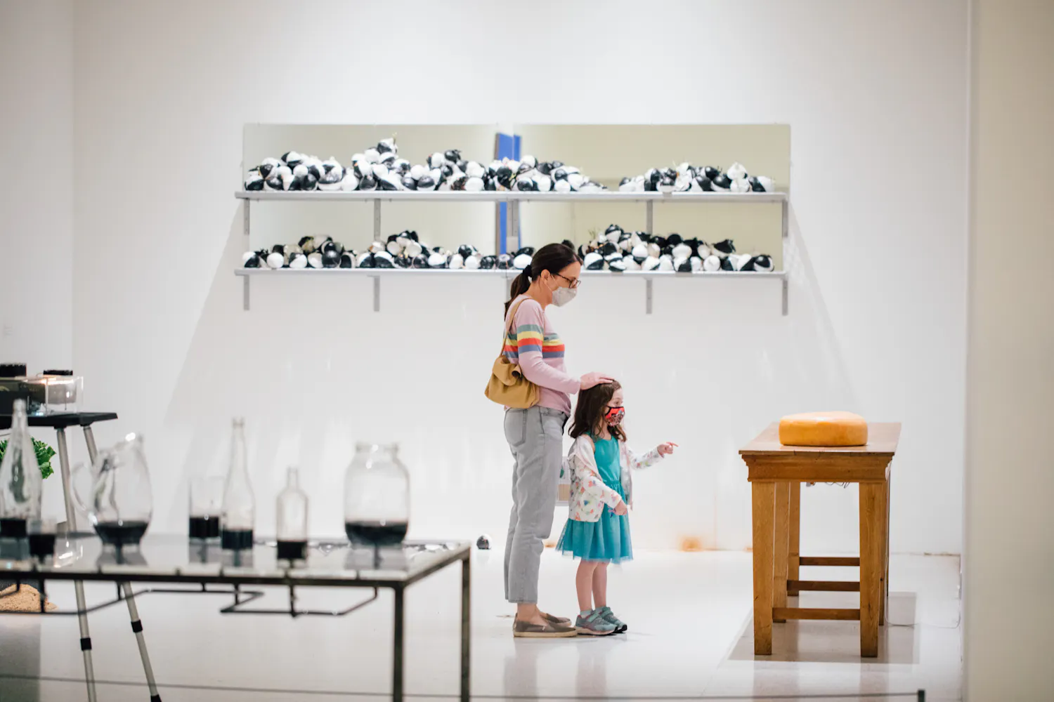 A woman and a girl stand in front of artwork in a gallery.