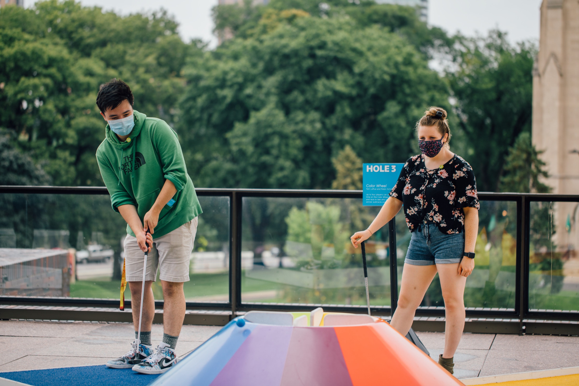 Two adults playing mini golf.