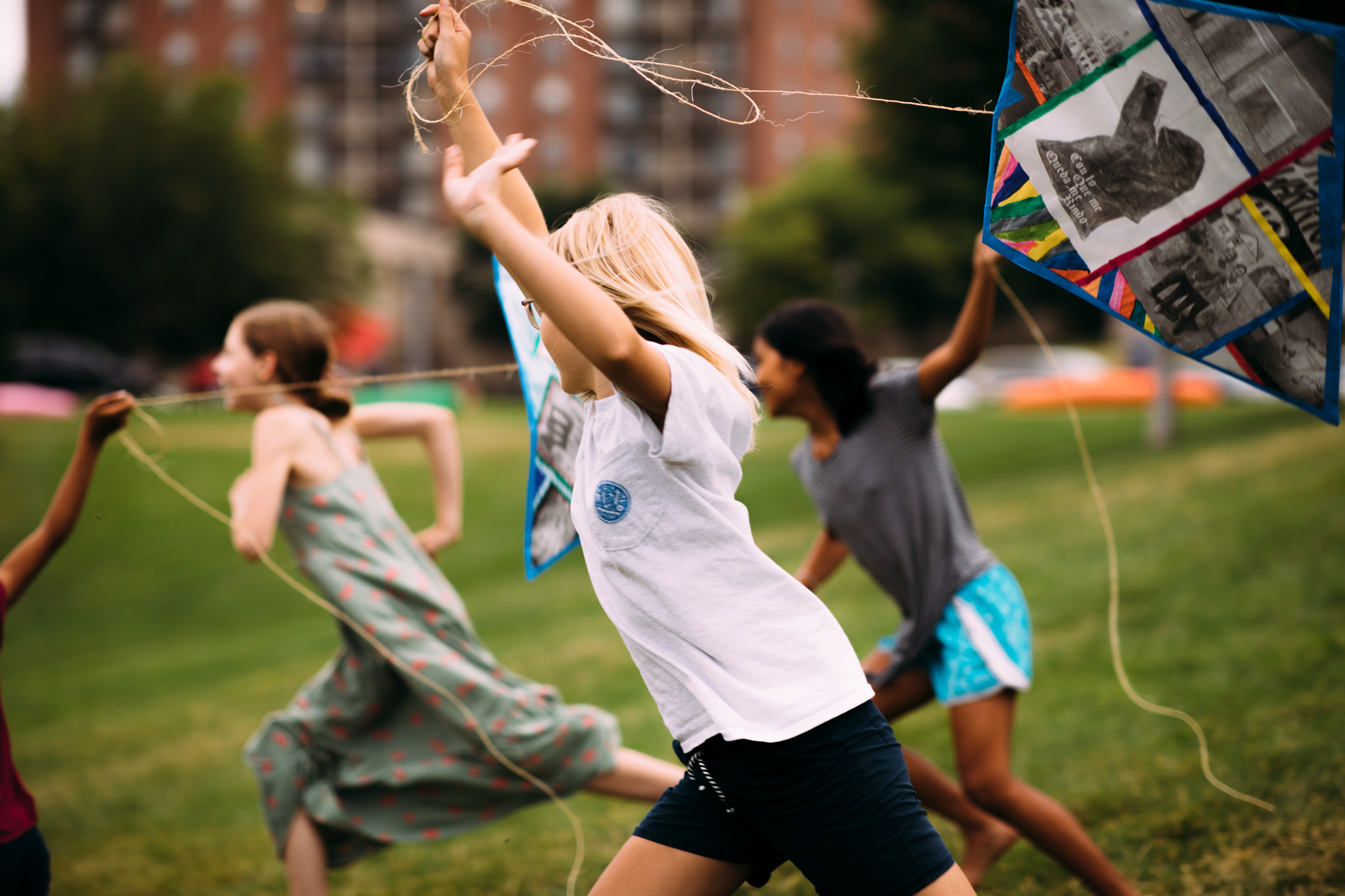 Children run outside while flying kites.