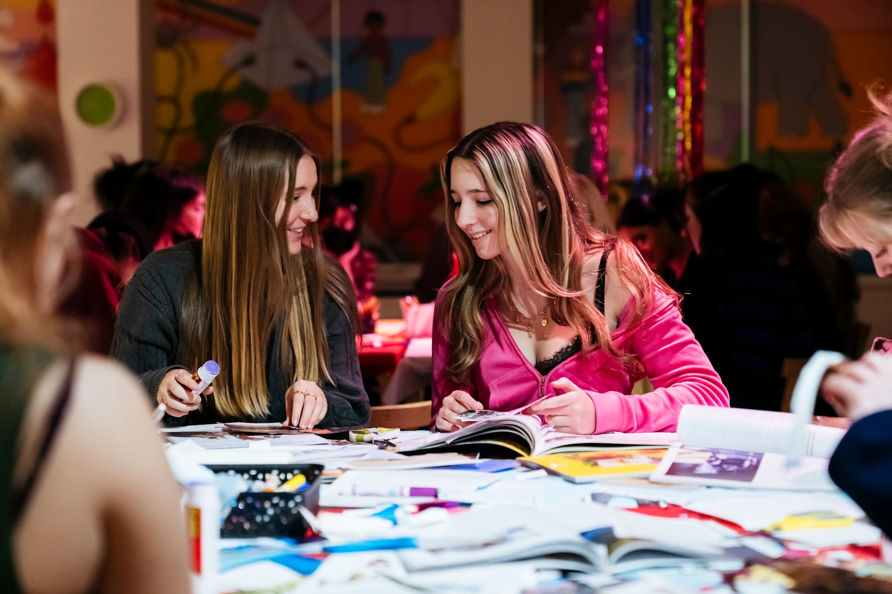 Two smiling teens make collages.