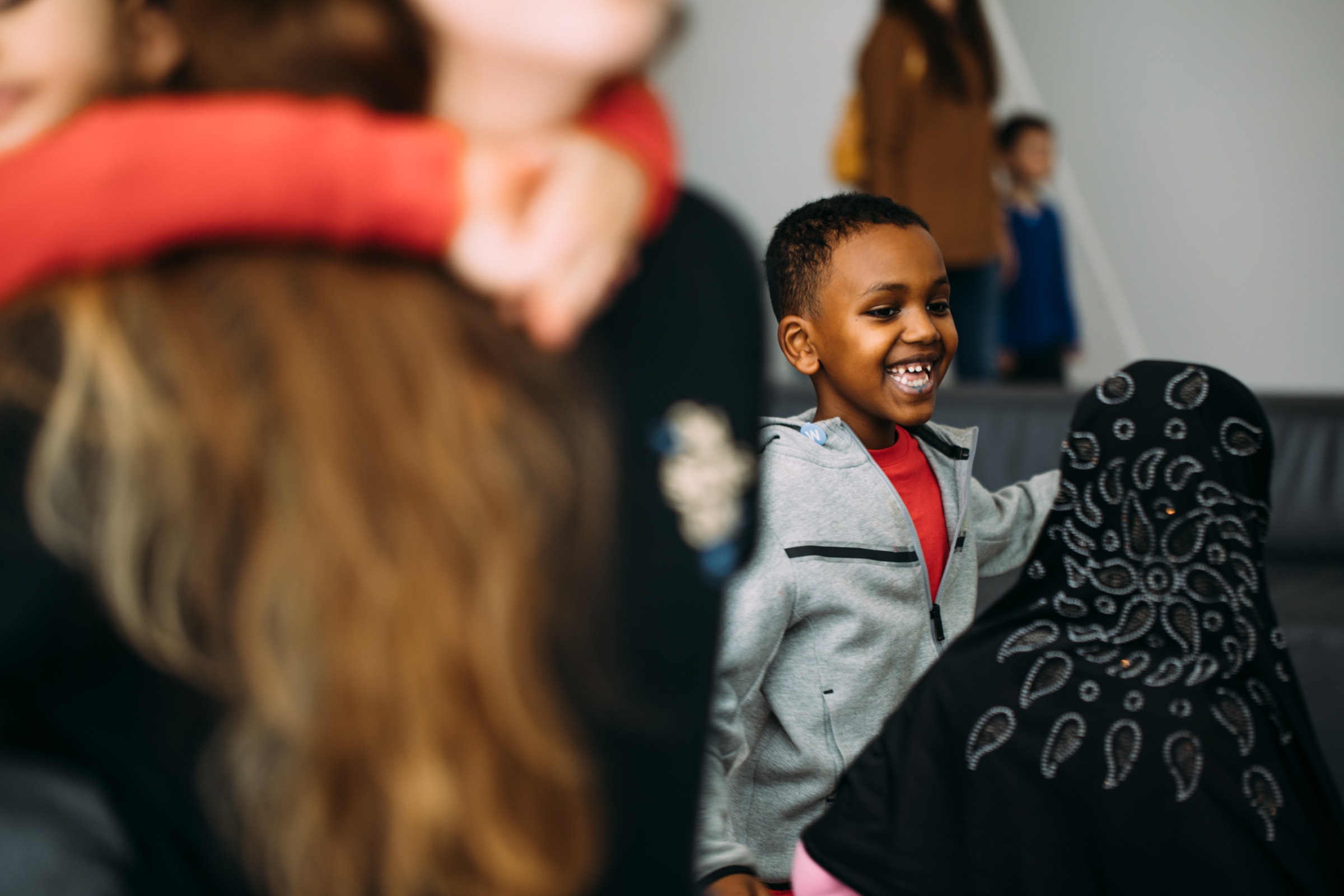 A child with dark skin smiles amongst a crowd of people in the foreground.