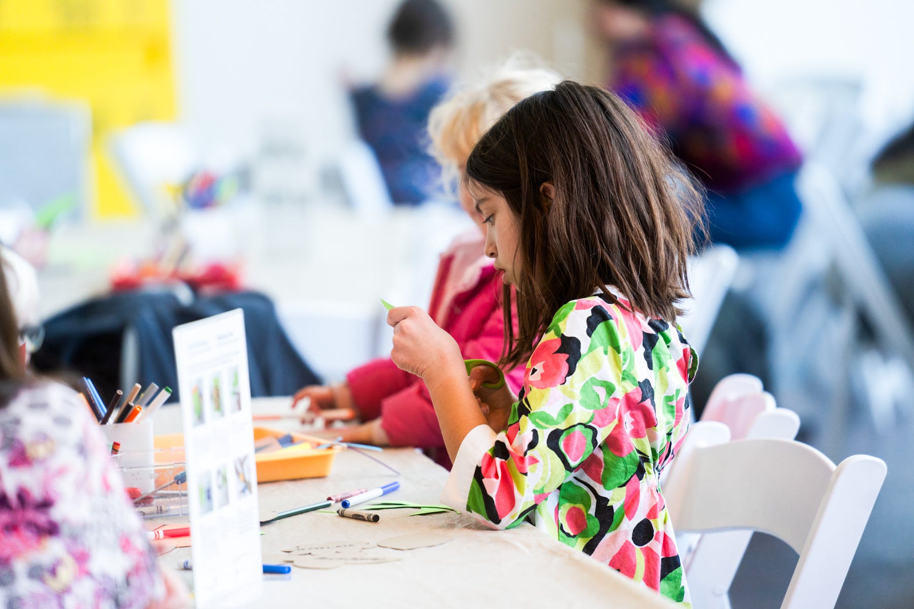 Two children sit at a table and make crafts.