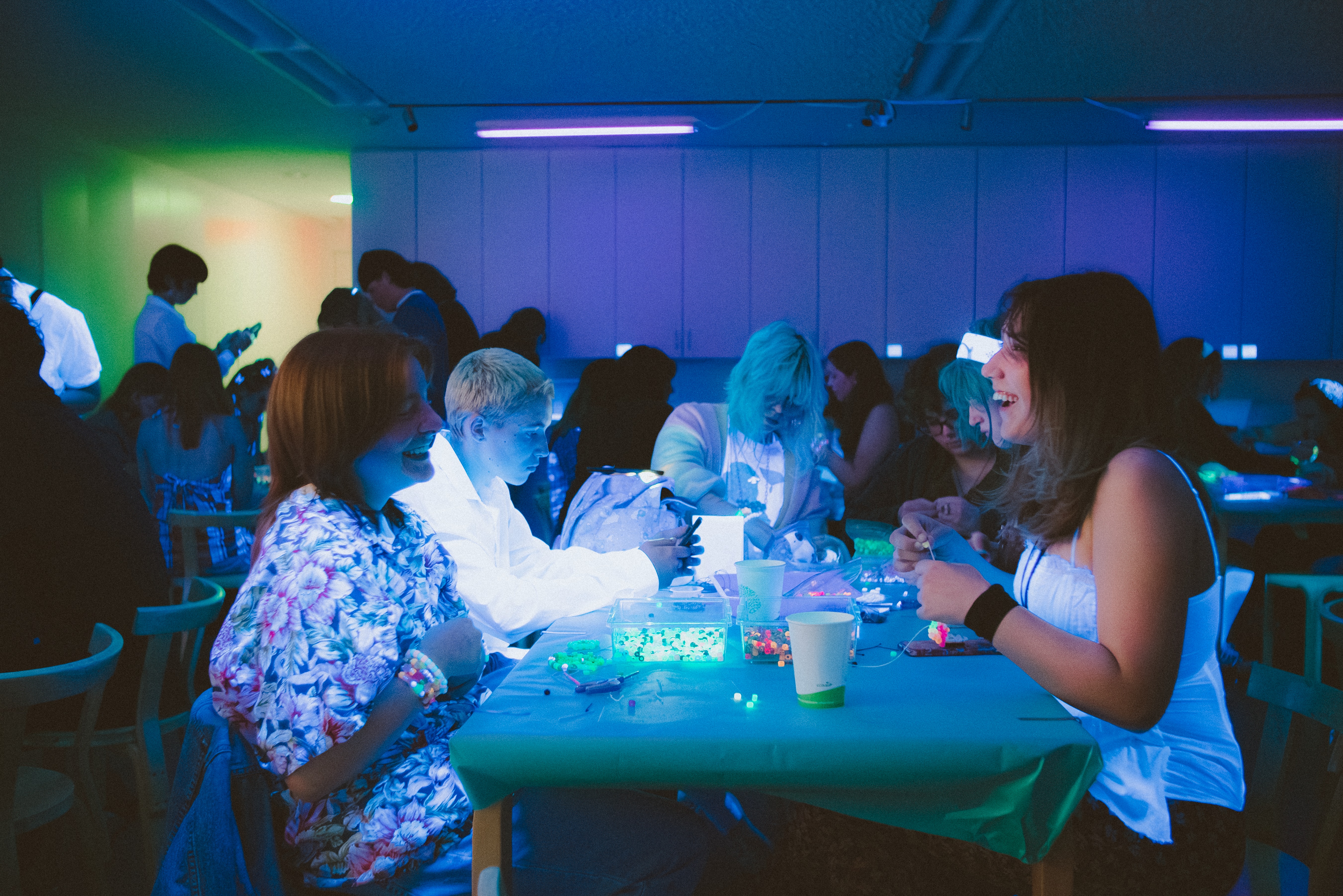 Teens work on artwork in a room filled with blacklight.
