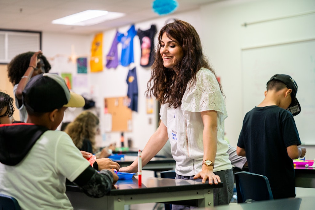 Top view of hands holding a small sketchbook, one is writing words and the other is holding the sketchbook open.