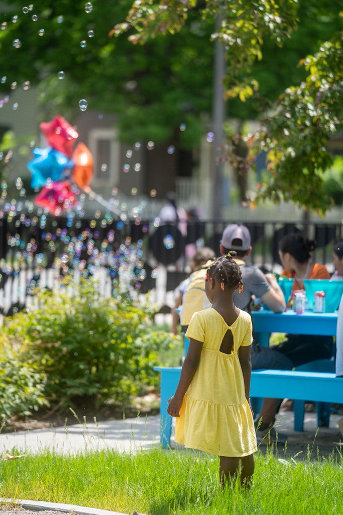 People pose for a photo with balloons and hats in front of a scenic backdrop, as others look on.