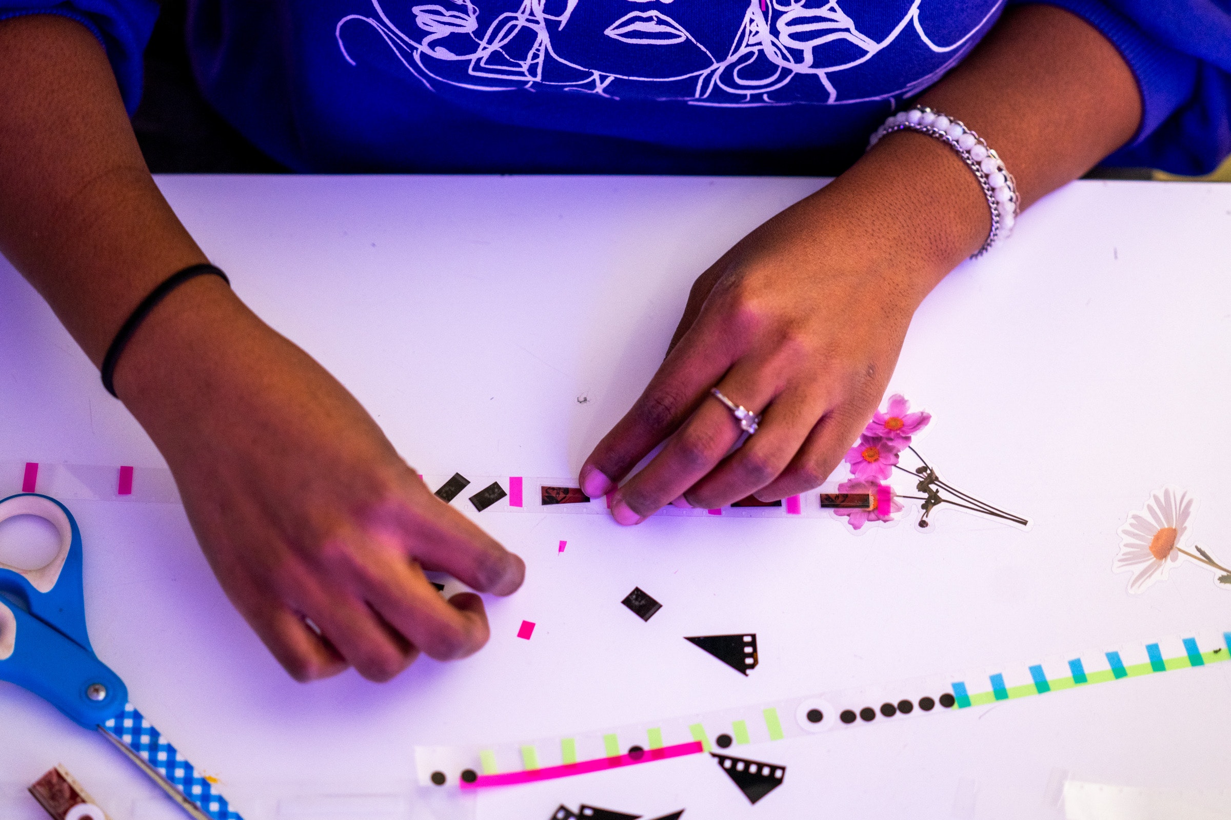 Top view of hands arranging cut up film and paper