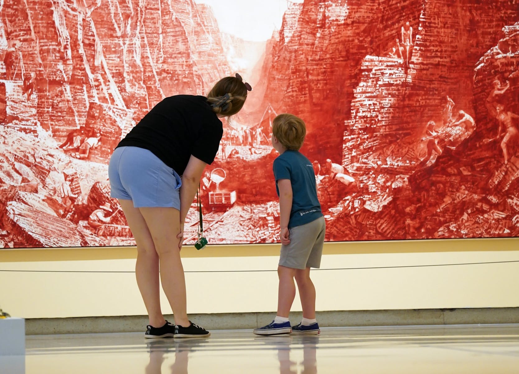 An adult and a child look at a piece of art