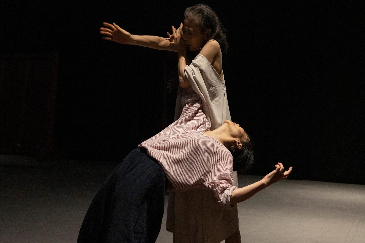 One performer with medium skin leans backward, one arm supported by another performer.