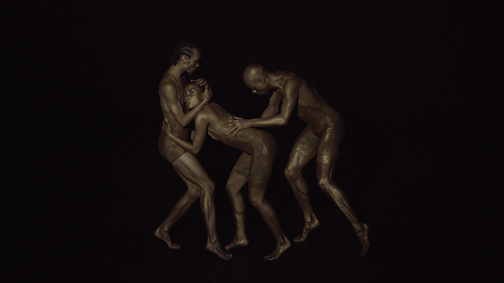 Three adults mid-pose in a black-box space, they are painted to look bronze.