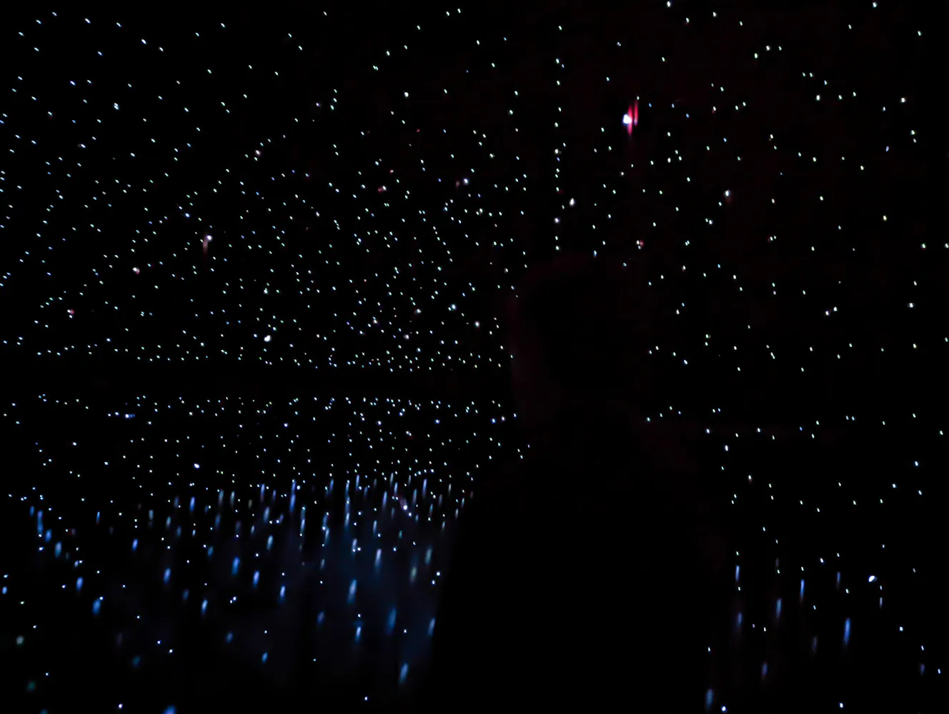 The outline of a figure can be seen amongst stars in darkness.
