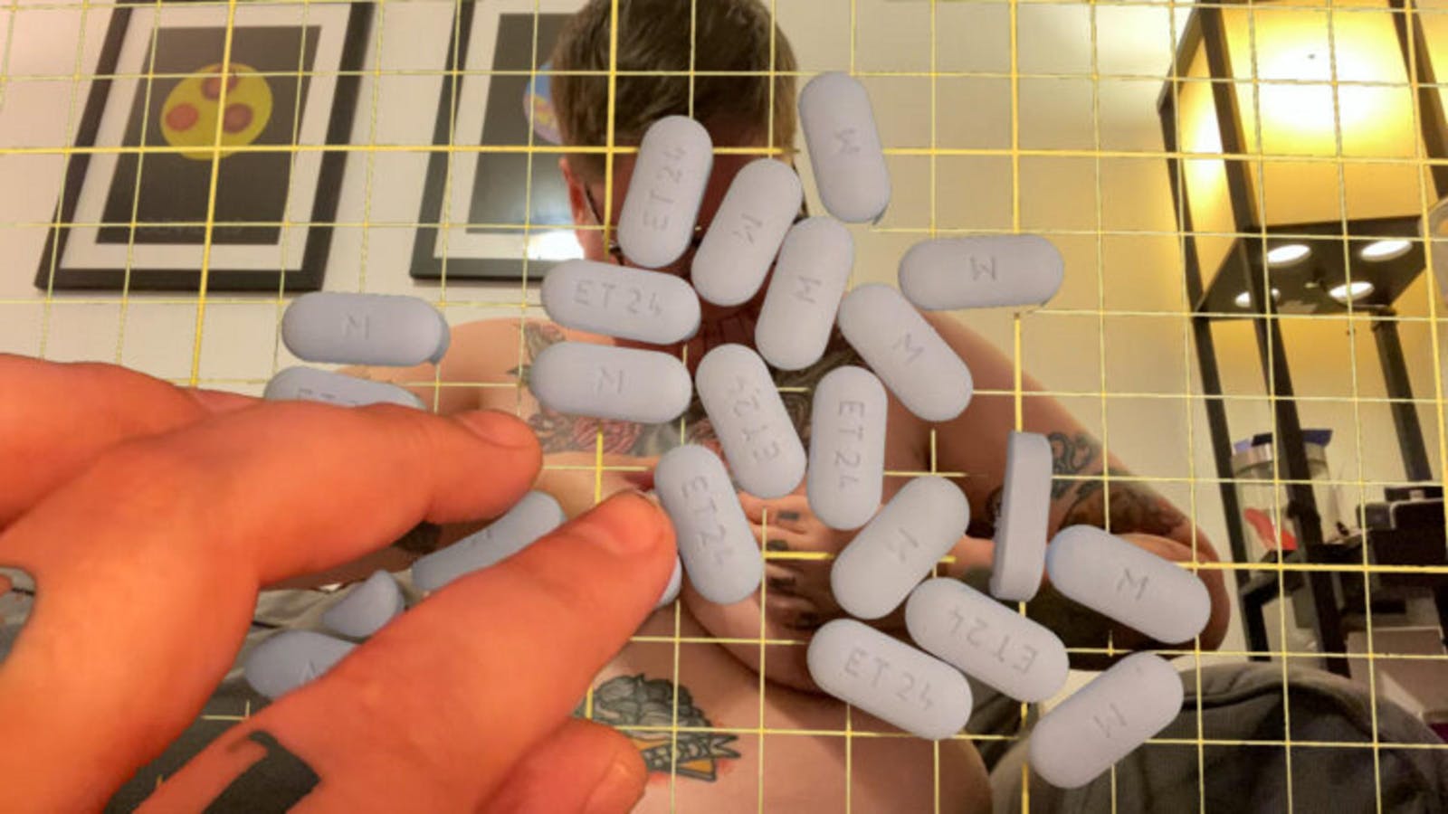 Composite image of fingers touching pills on a surface, a yellow grid pattern, and a photo of a nude person in the background.