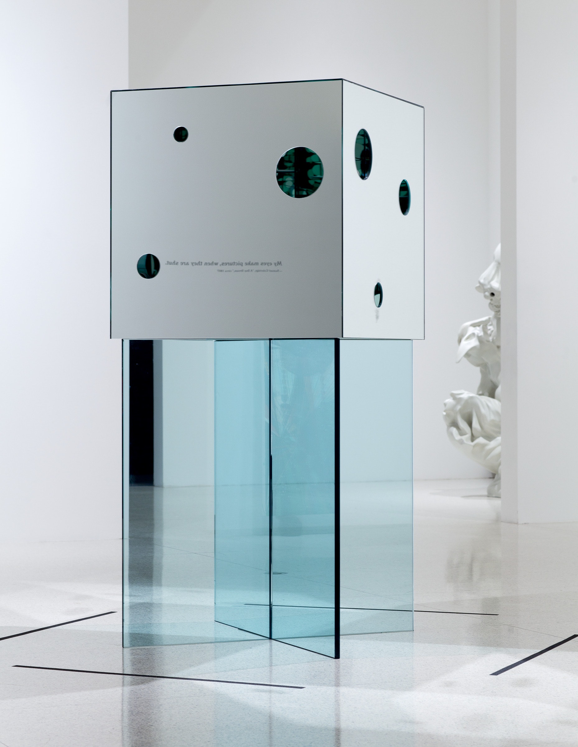 An art object with translucent blue legs sits in a space.