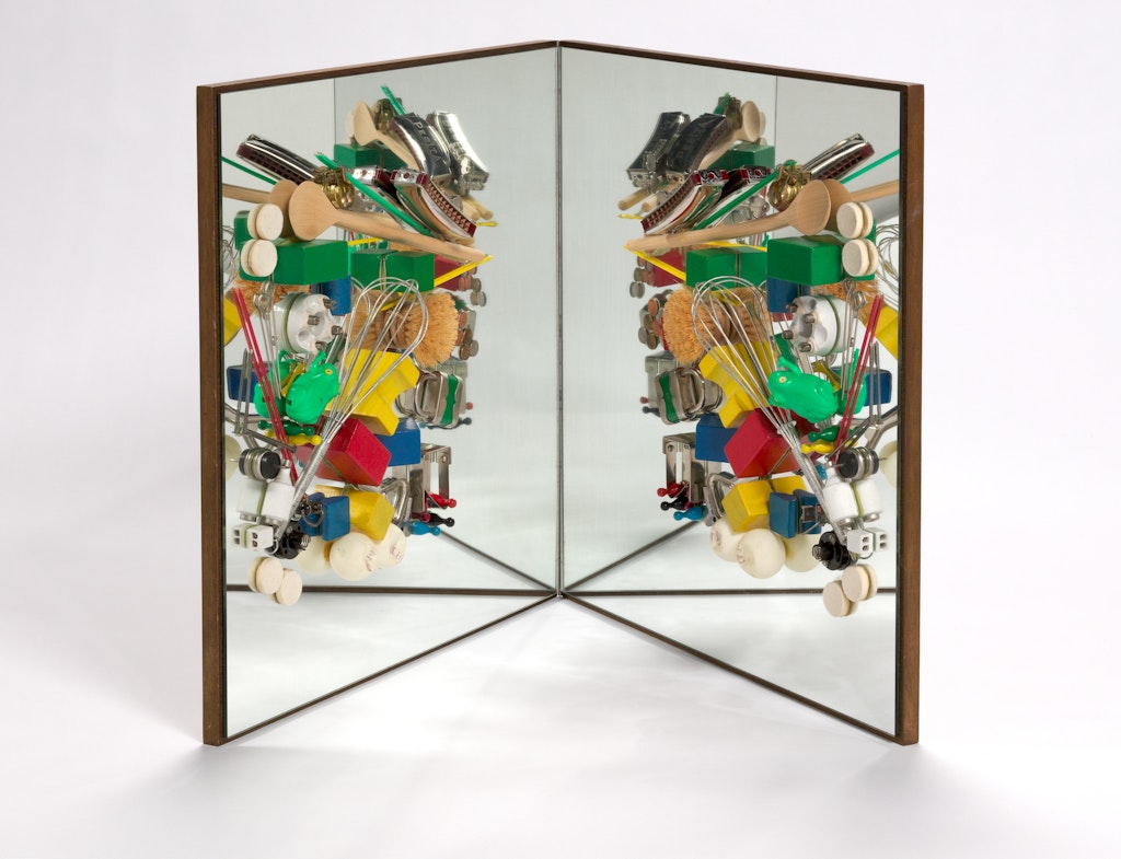 A sculpture made of a mirror with objects and utensils glued to the face