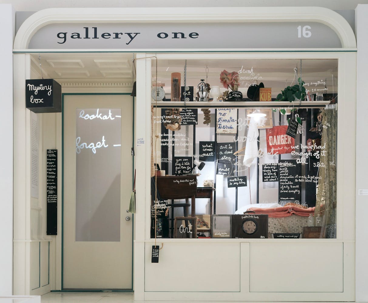 An artwork that is a recreation of the exterior door and window of a shop filled with strange objects.