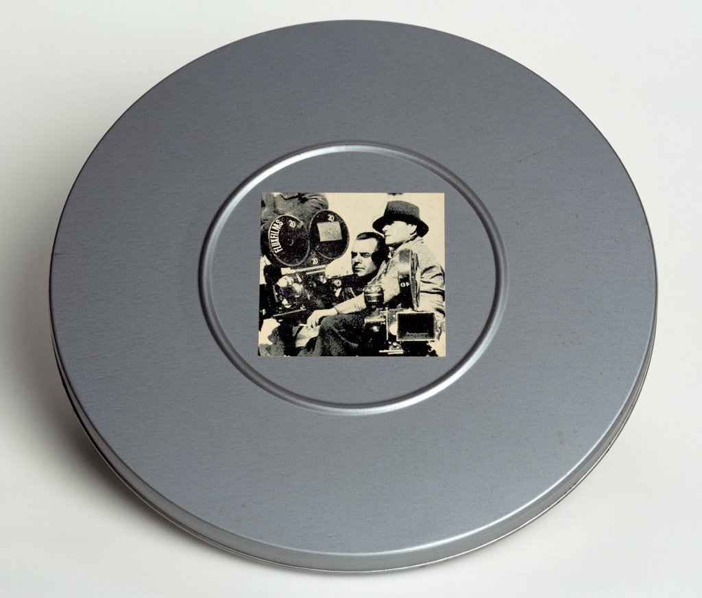 A silver film canester with a black and white photograph of directors on the front.