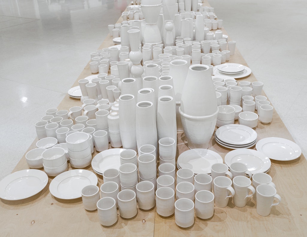 A table full of white ceramic cups, bowls and vases.