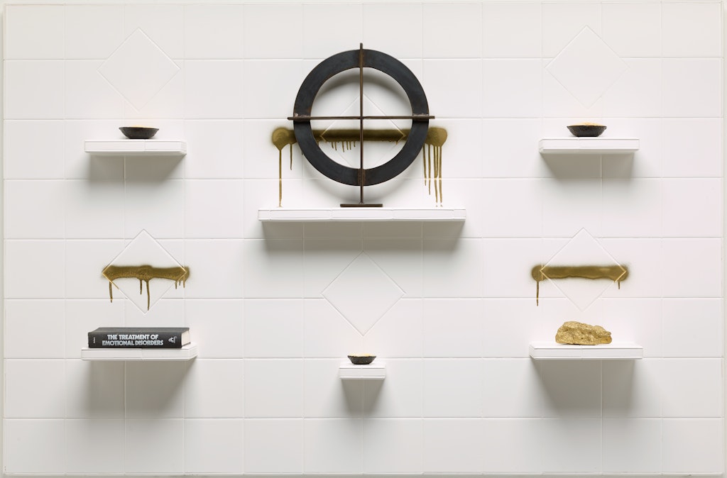 Various objects on white shelves on a white tiled wall.