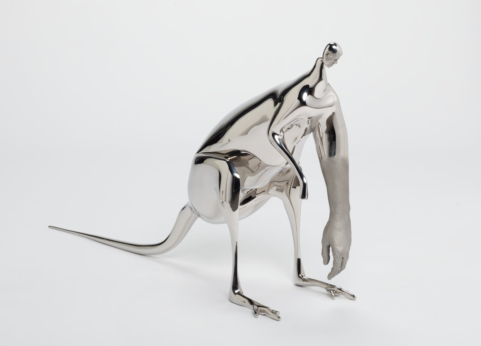 A silver sculpture that looks like a kangaroo with a human head and a large hand