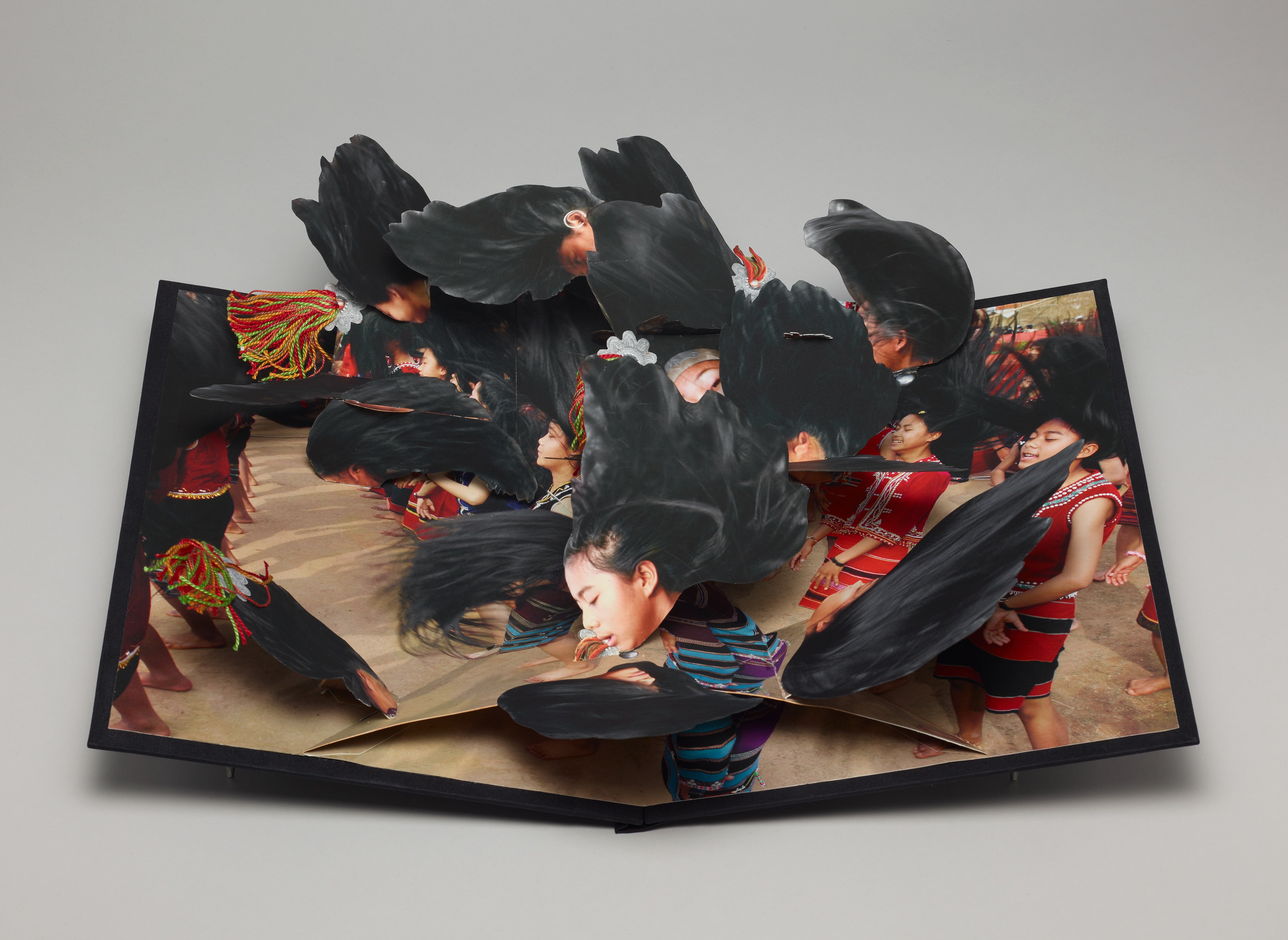 A open pop out book depicting hair from many young adults in paper.