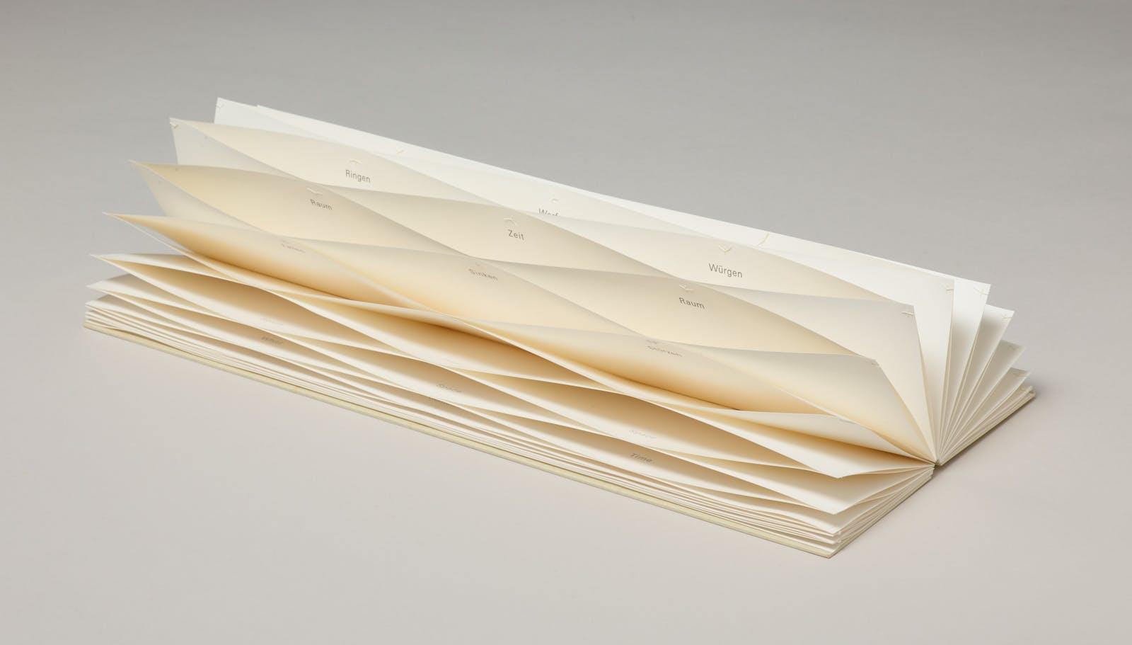 A long thin book is opened up to pages that are connected to create a honeycomb effect.