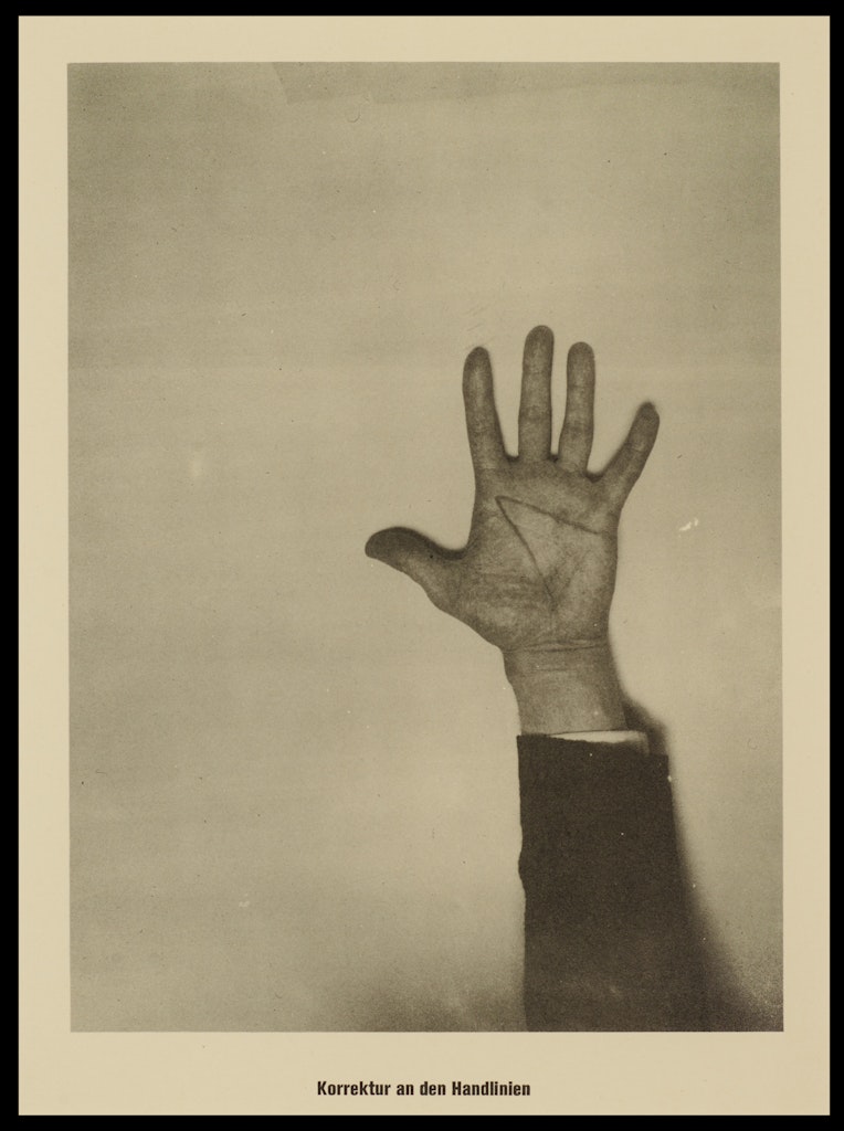 A black and white photograph of a hand reaching up.