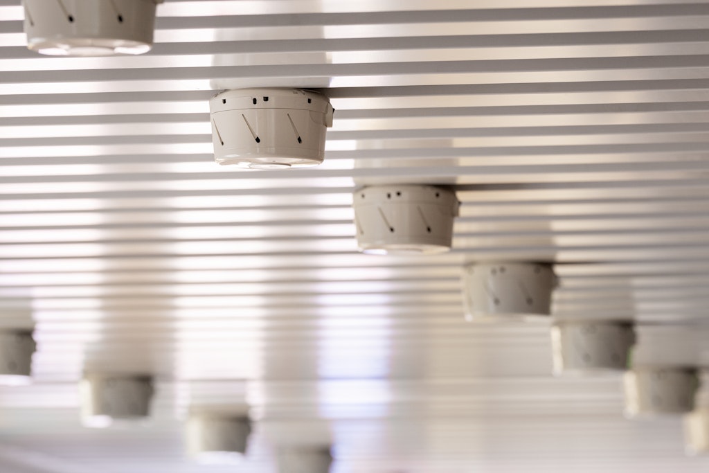 Several fire alarms on a ceiling in a row