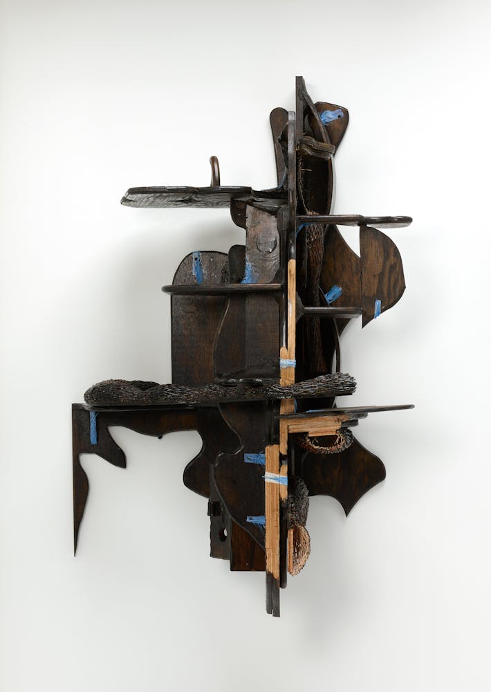 An wooden object sculpture on a white wall.