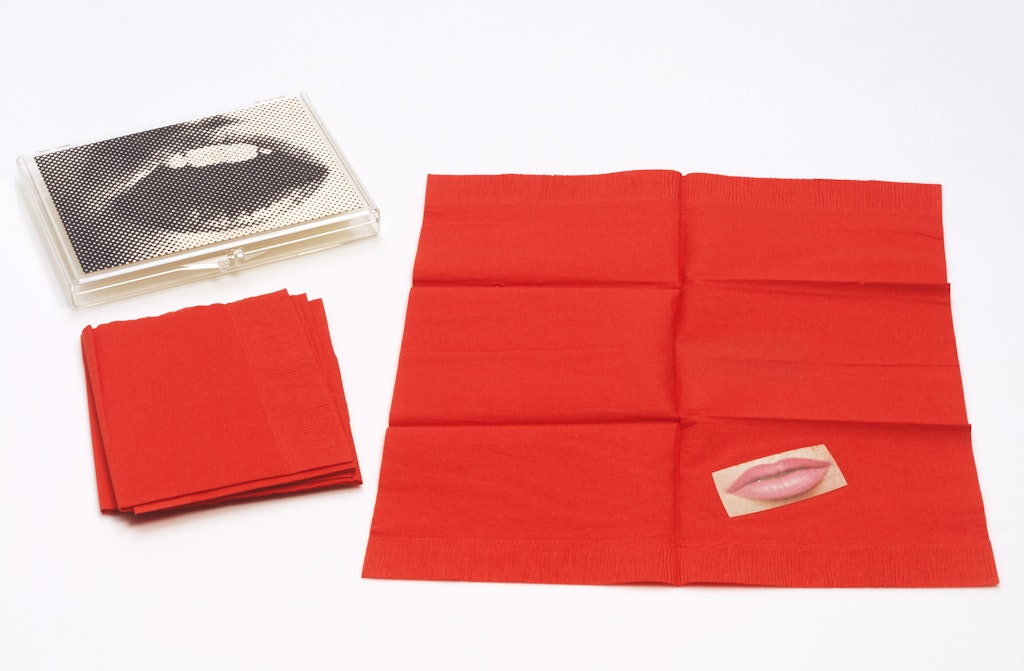 A table top view of red napkins and a case with an image of lips on the top