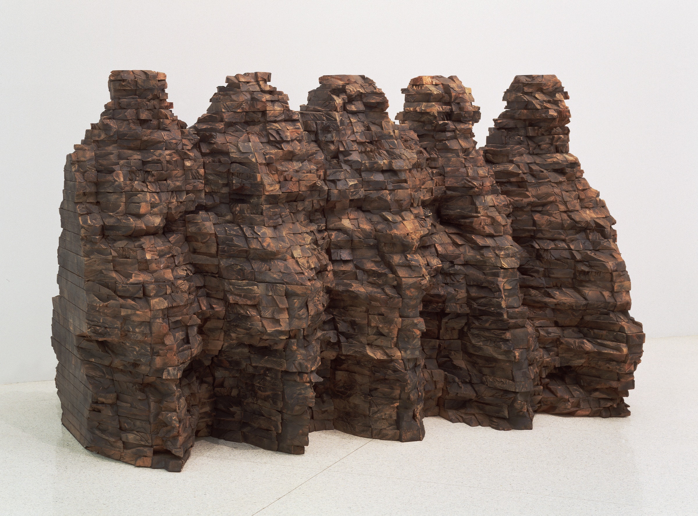 A sculpture of layers of brown wood, shaped like mountains.