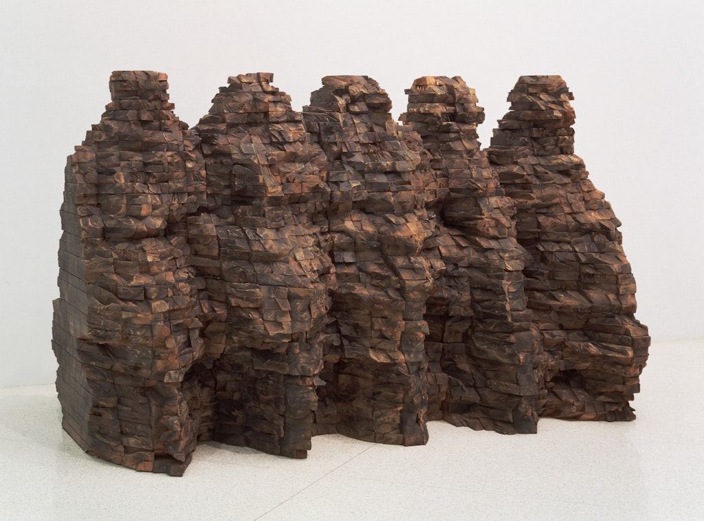 A sculpture of layers of brown wood, shaped like mountains.