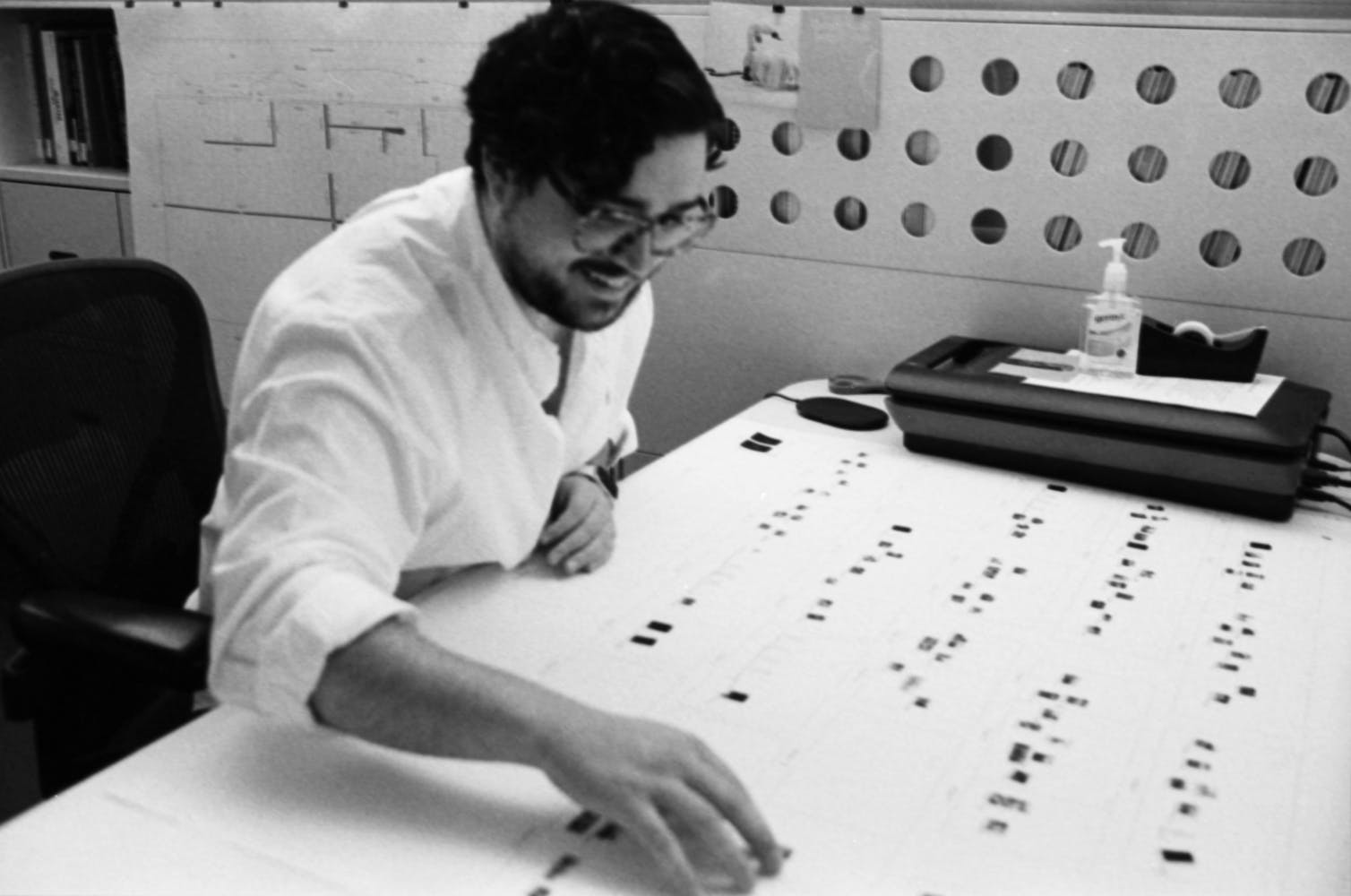 A man smiles while working at a desk in an office.