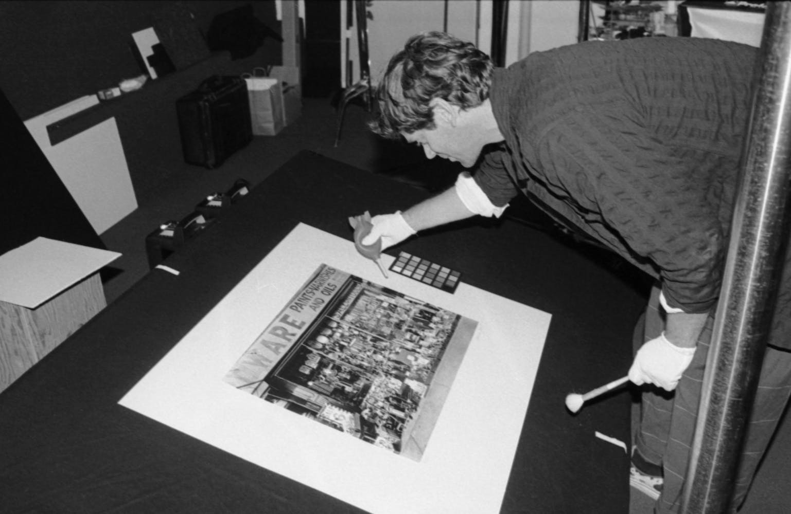 A man sprays air on a photograph on a photography station.