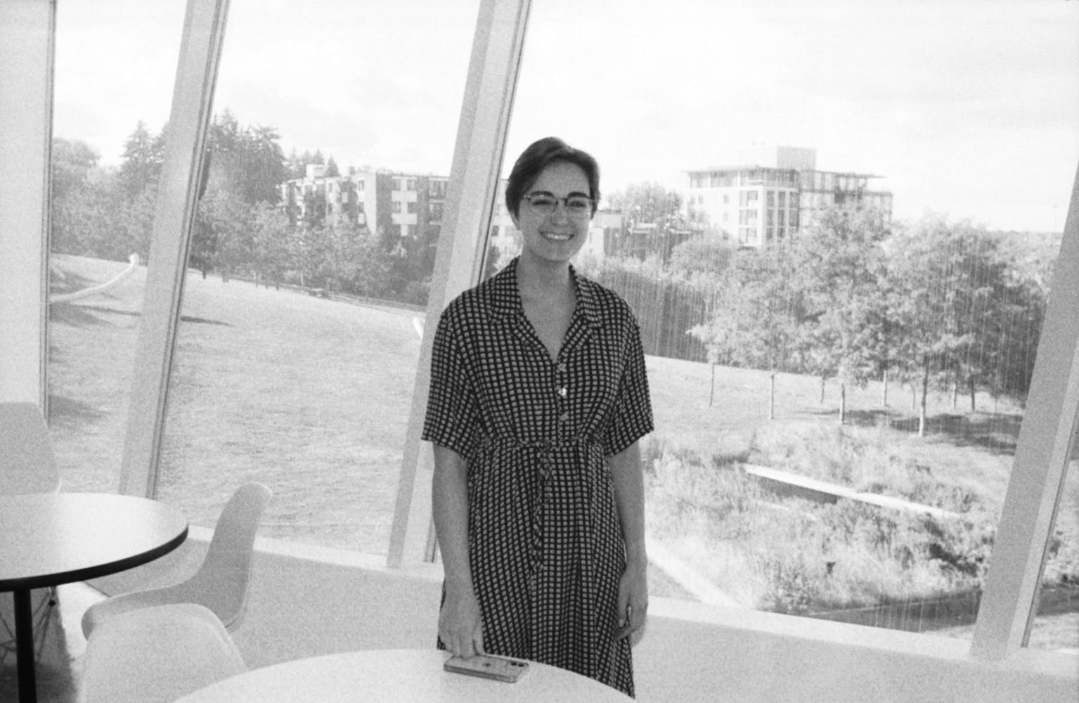 A woman stands in a museum offices smiling while lookinng at the viewer.